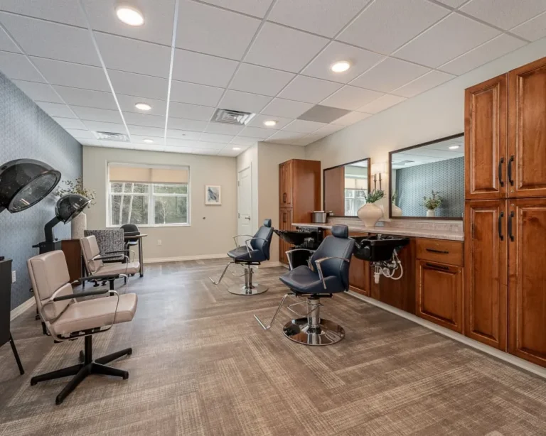 Modern hair salon interior with blue styling chairs, wash stations, and a long wooden cabinet with mirrors along the wall.